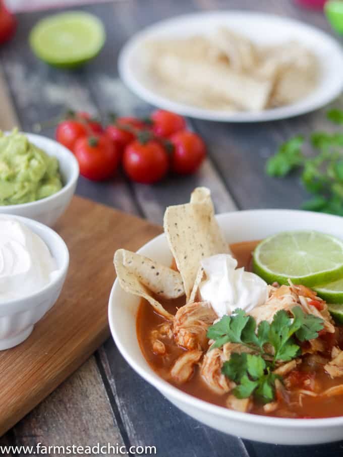 This Paleo and Whole30 Chicken Tortilla Soup is delicious, healthy and so easy to make! Just combine chicken breasts, onion and tomatoes in the slow cooker along with a few common spices like chili powder, garlic and cayenne and you have a scrumptious one pot slow cooker dinner! Garnish with limes, cilantro + avocado! 