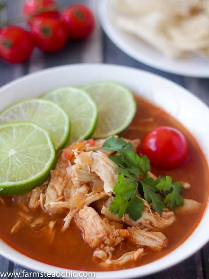 This Paleo and Whole30 Chicken Tortilla Soup is delicious, healthy and so easy to make! Just combine chicken breasts, onion and tomatoes in the slow cooker along with a few common spices like chili powder, garlic and cayenne and you have a scrumptious one pot slow cooker dinner! Garnish with limes, cilantro + avocado! 