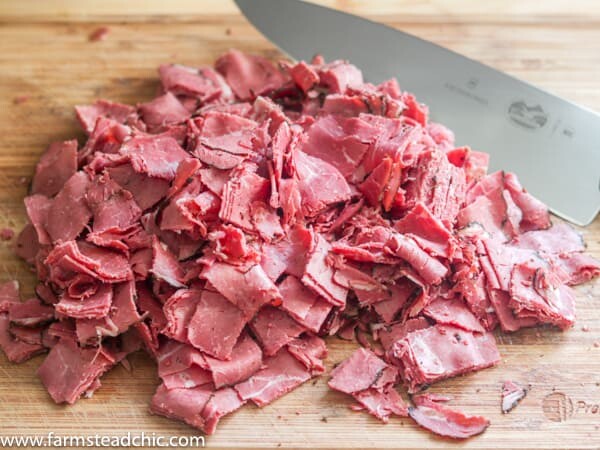 Chopped corned beef on a cutting board with a chef's knife