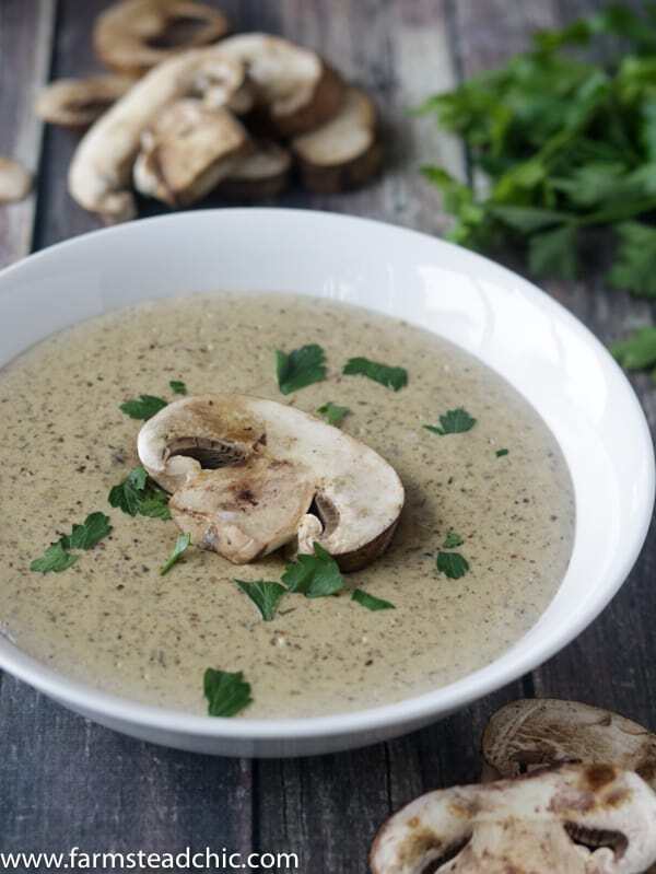 Keto Cream of Mushroom Soup in a white bowl on a dark barn wood background with fresh mushrooms and parsley.