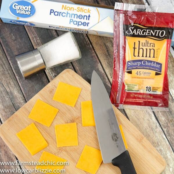 keto crackers with a cutting board and knife, slices of fresh cheese and a salt grinder